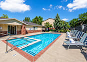 Thumbnail 3 of 4 - A swimming pool surrounded by lounge chairs and a building in the background.