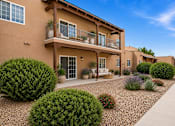 Thumbnail 4 of 24 - A row of houses with a gravel driveway and landscaping in front.