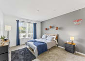 Thumbnail 5 of 23 - a bedroom with a bed and a window with blue curtains