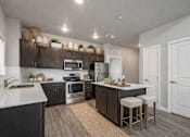 Thumbnail 15 of 21 - Kitchen with white countertops and island seating at Harper Ridge Apartments, Meridian, ID 83642