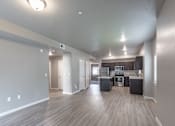 Thumbnail 7 of 29 - A spacious kitchen and living room with wood flooring and white walls.