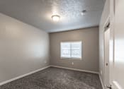 Thumbnail 13 of 29 - A room with a carpeted floor and a window with blinds.