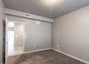 Thumbnail 12 of 29 - A room with a carpeted floor and a door leading to another room.