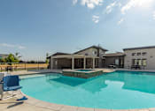 Thumbnail 27 of 29 - A swimming pool in front of a house with a sunny sky.