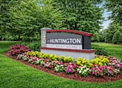 Thumbnail 10 of 13 - A sign for Huntington Apartment Homes is surrounded by flowers.