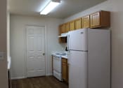 Thumbnail 5 of 16 - an empty kitchen with white appliances and wooden cabinets and a refrigerator