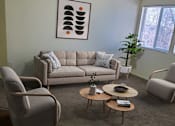 Thumbnail 2 of 16 - A living room with a grey couch, two grey armchairs, and a coffee table.
