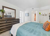 Thumbnail 8 of 23 - a bedroom with a bed and a dresser and a mirror