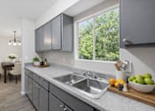 Thumbnail 12 of 15 - A modern kitchen with a large window and a dining table.
