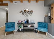 Thumbnail 11 of 24 - A room with two blue chairs and a table with various objects on it.