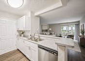 Thumbnail 16 of 21 - Open concept kitchen with white cabinetry and living area at Northview Park Apartments, Michigan, 48310