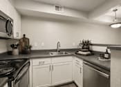 Thumbnail 8 of 11 - A kitchen with white cabinets and a black stove top.