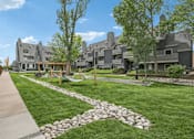 Thumbnail 2 of 11 - A residential area with houses and a grassy area with a stone path.