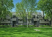 Thumbnail 1 of 11 - A large house with a grey exterior and a green lawn in front.