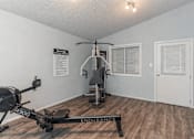 Thumbnail 5 of 11 - A gym room with a rowing machine and a bench.