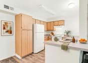 Thumbnail 6 of 11 - A kitchen with wooden cabinets and a white refrigerator.