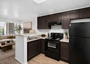 Thumbnail 23 of 28 - A kitchen with black appliances and brown cabinets.