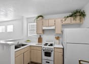 Thumbnail 24 of 28 - A white kitchen with wooden cabinets and a white stove.