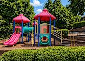 Thumbnail 7 of 12 - A playground with a red slide and a blue and green play structure.