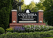Thumbnail 1 of 12 - A sign for Columbia W.O.D. Townhomes is displayed in front of a green hedge.