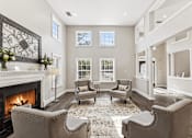 Thumbnail 8 of 12 - A living room with a fireplace and grey chairs.