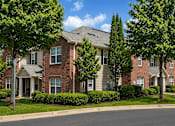 Thumbnail 3 of 12 - A row of red brick houses with green trees in front.