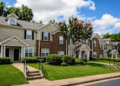Thumbnail 9 of 12 - A row of houses with green lawns and trees.