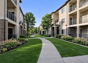 Thumbnail 3 of 17 - A long concrete walkway leads between two rows of apartment buildings.
