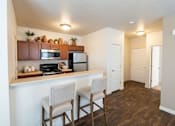 Thumbnail 15 of 17 - A kitchen with a white counter and brown chairs.
