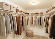Thumbnail 16 of 17 - A well organized walk in closet with clothes hanging on shelves and a round ottoman.