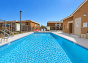 Thumbnail 8 of 30 - A large swimming pool in front of a building with a metal fence and stairs.