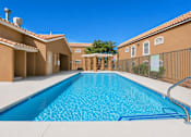 Thumbnail 7 of 30 - A swimming pool in a residential area with a clear blue sky.