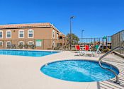Thumbnail 9 of 30 - A swimming pool with a slide and a building in the background.
