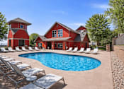 Thumbnail 2 of 21 - Red clubhouse building with resort style swimming pool at Stetson Meadows Apartments, Colorado Springs, CO 80922