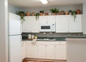 Thumbnail 10 of 10 - A kitchen with white cabinets and a white refrigerator.