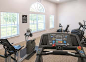 Thumbnail 4 of 10 - A row of stationary bikes in a gym with a clock on the wall.