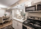Thumbnail 19 of 20 - A modern kitchen with a black stove top oven and a black microwave above the counter.