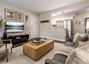 Thumbnail 18 of 20 - A living room with a wooden coffee table and a grey sofa.