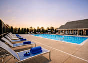 Thumbnail 8 of 20 - A poolside area with sun loungers and a building in the background.