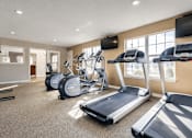 Thumbnail 10 of 20 - A spacious gym with treadmills, elliptical machines, and a television.
