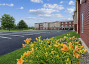 Thumbnail 4 of 24 - A parking lot with a building in the background and orange flowers in the foreground.