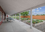 Thumbnail 13 of 24 - A patio with a table and chairs is covered by a white roof.