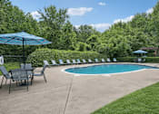 Thumbnail 2 of 14 - A pool surrounded by lawn chairs and umbrellas.