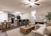 Thumbnail 8 of 12 - A well-lit living room with a dining area and kitchen in the background.