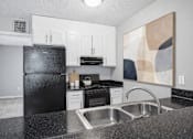 Thumbnail 14 of 18 - Modern kitchen with black appliances and granite countertops at Davidson Homes Apartments, Concord, North Carolina