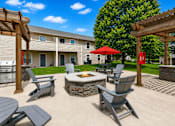 Thumbnail 6 of 20 - A patio with a fire pit and chairs.
