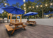 Thumbnail 6 of 28 - A wooden picnic table with a blue umbrella is set up on a wooden deck. at Epic Apartments , Daytona Beach, FL, 32114