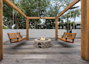 Thumbnail 4 of 28 - A fire pit is surrounded by two wooden benches and a wooden pergola at Epic Apartments , Daytona Beach