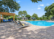 Thumbnail 3 of 28 - A pool surrounded by trees and chairs at Epic Apartments , Daytona Beach, 32114