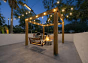 Thumbnail 5 of 28 - A wooden pergola with lights and a bench is set up in a courtyard. at Epic Apartments , Apartments, Daytona Beach, FL